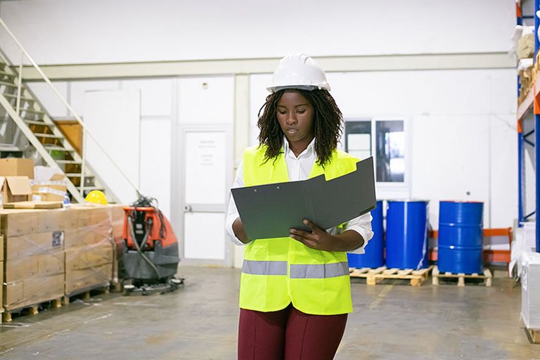 logistic employee in hardhat and safety vest walking in wareho